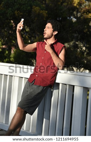 Young man taking a selfie outdoors making a goofy face