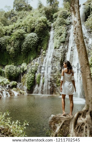 stylish young asian woman taking picture for social media in beautiful waterfall