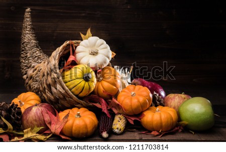 A Thanksgiving holiday decorative cornucopia with pumpkins, squash, leaves etc Royalty-Free Stock Photo #1211703814