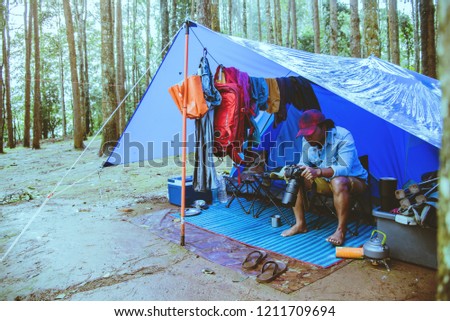 Asian man relax travel nature in the holiday.Take a picture Nature Study in the Jungle camping on the Mountain. rainy season at Chiangmai in Thailand.