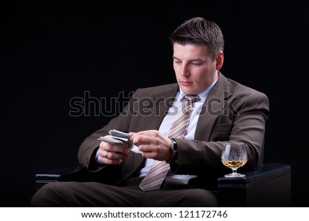 Young businessman with money and an alcoholic beverage sitting in the chair