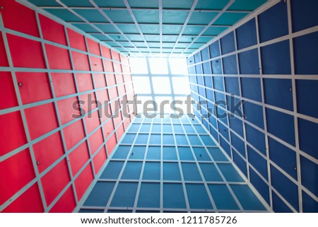 Abstract perspective of vertical lobby ceiling with skylight and strong geometry and symmetry and dramatic colors as background with space for copy
