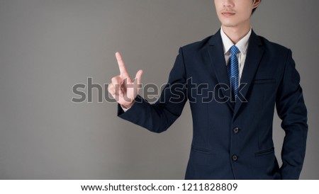 Business man is touching on virtual screen , grey background in studio 
