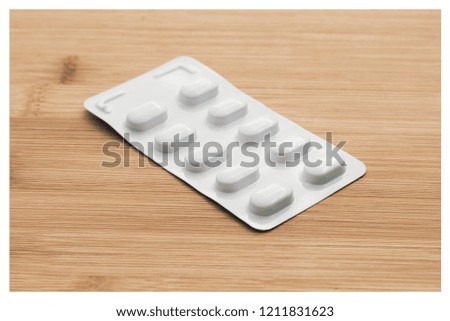 Medical pills isolated on a wooden table top. This image can be used to represent  prescription medicine. 