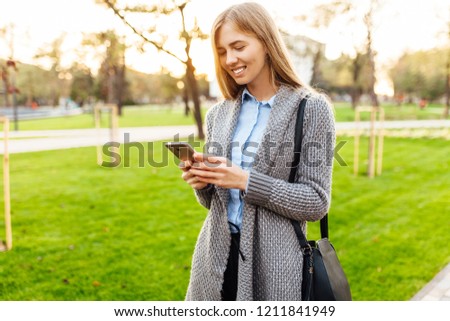 Happy smiling woman using phone on city street. against the backdrop of a beautiful sunset
