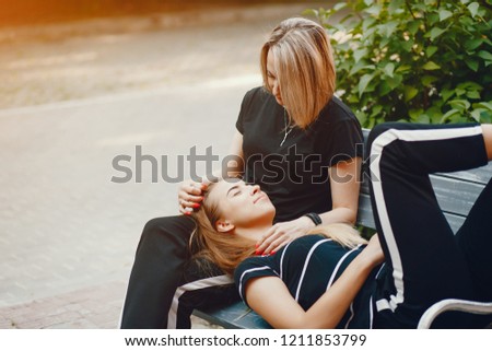 Mother and daughter sitting on a bench. Family in a city. Two ladies in a summer town