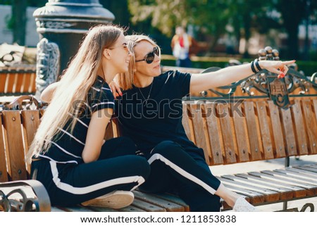 Mother and daughter sitting on a bench. Family in a city. Two ladies talking.