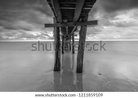 Fine art black and white image of an old jetty at the beach in Kuala Penyu, Sabah. Soft focus due to long exposure.