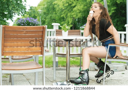Happy woman wearing roller skates enjoying her free time while eating ice cream during summer sunny weather.
