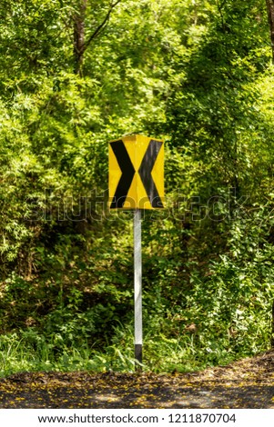 Sakon Nakhon, Thailand, OCTOBER 1, 2018. Yellow traffic sign curved warning on a road and forest background.