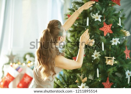 Seen from behind modern housewife decorating the Christmas tree