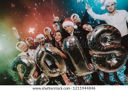 Smiling People with Baloons Celebrating New Year. Celebrating of New Year. Young Woman in Dress. Young Man in Suit. Santa Claus Cap. People with Gray Baloons. Happy New Year. People Have Fun.