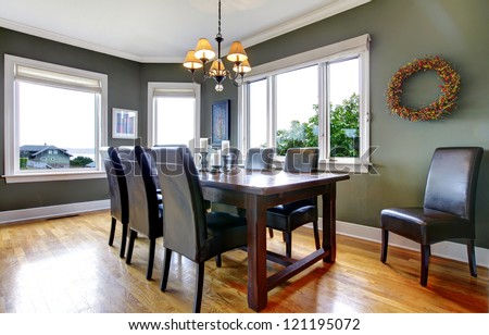 Large green dining room with leather chairs and large windows.