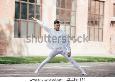 handsome young dancer performing modern dance on street 