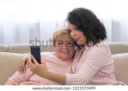 Asian senior woman and daughters taking picture with mobile phone