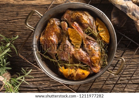Roasted duck legs in pan with oranges herbs red cabbage and potato pankaces.