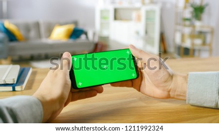 First Person Close-up of the Man Holding Green Screen Smartphone in Landscape Mode and Playing Game with His Thumbs.