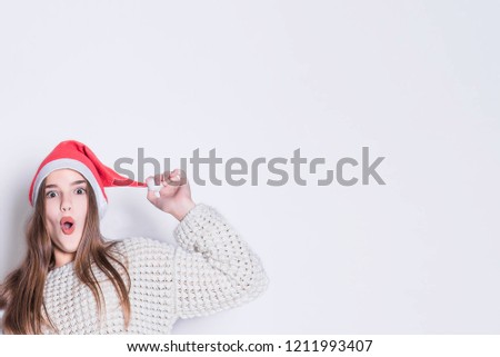 x-mas, people, sale concept. Portrait of happy teenage girl in santa claus hat and white warm sweaters. Merry Christmas and Happy Holidays concept. Family holiday, party over white background.