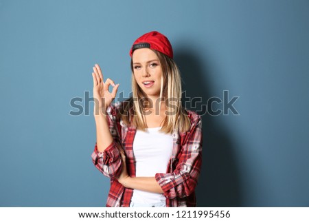 Beautiful young woman showing OK gesture on color background