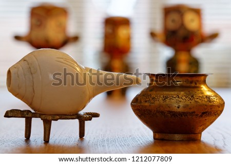 Conch shell with brass water pot and Hindu deity Lord Jagannath in the blurry background