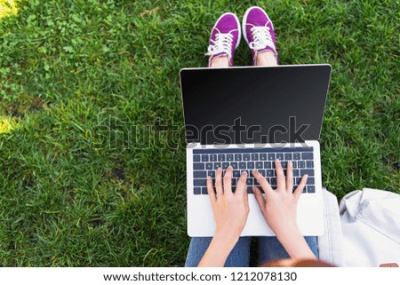 cropped image of freelancer using laptop with blank screen in park