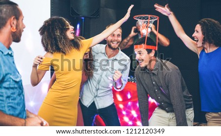 Group of happy people playing funny basketball game inside pub cocktail bar - Young friends having fun hanging out and laughing together - Trends, nightlife and friendship concept - Focus on right man