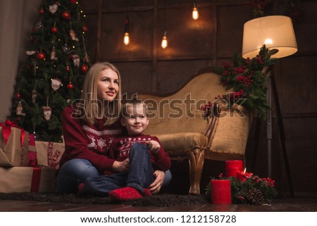Portrait of mother and son in sofa near Christmas tree. Happy new year concept.