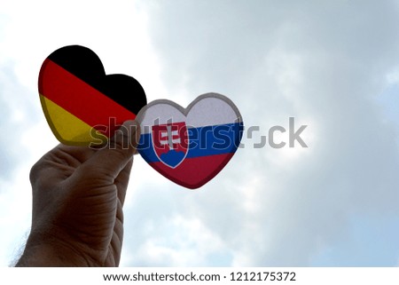 Hand holds a heart Shape Germany and Slovakia flag, love between two countries