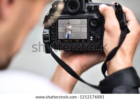Digital single-lens reflex camera in hands. Photographer shooting hands close up. Man photographer makes photos for stock photography. Male hands hold the camera close-up