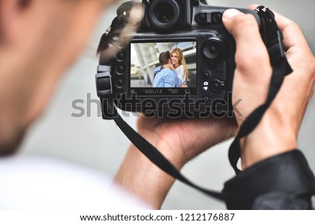 Digital single-lens reflex camera in hands. Photographer shooting hands close up. Man photographer makes photos for stock photography. Male hands hold the camera close-up Royalty-Free Stock Photo #1212176887