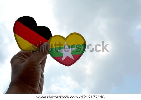 Hand holds a heart Shape Germany and Myanmar flag, love between two countries