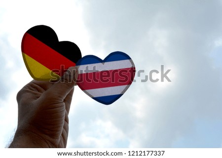 Hand holds a heart Shape Germany and Costa Rica flag, love between two countries