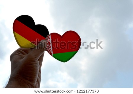 Hand holds a heart Shape Germany and Belarus flag, love between two countries