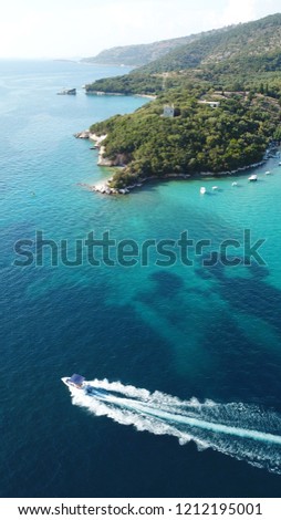 Aerial drone bird's eye view of popular beach of Zeri with beautiful emerald sandy beach full of sunbeds and sail boats at summer time, Epirus, Ionian, Greece