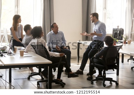 Male team leader boss talking to diverse business people at office meeting, multiracial employees group listening to ceo mentor coach speaking explaining new idea at corporate training or briefing Royalty-Free Stock Photo #1212195514