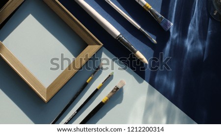 Brushes and frame on blue background. Paint. Flat lay, top view. Modern art concept. Artist. 