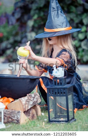 Adorable little girl wearing witch costume on Halloween at autumn day and having fun outdoors. Trick or treat.