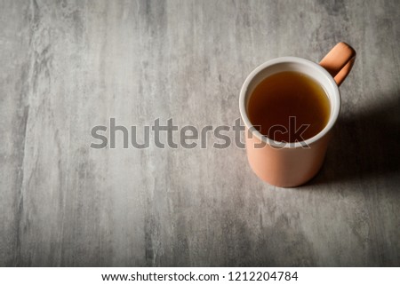 top view of peach-colored cup of tea which stands on gray background