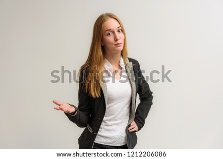 Studio portrait on the camera of a smiling beautiful girl with long hair talking on a white background with emotions. She stands right in front of the camera in various poses and looks happy.