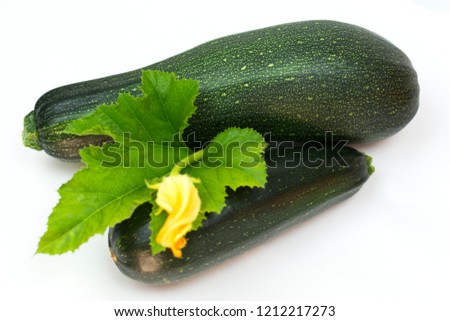 Green zucchini with leaves and flower close-up on white background