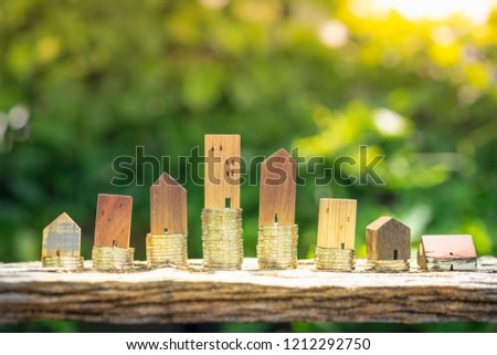 Wood house model and row of coin money on wood table with blur green leaves nature background, Real Estate market, Trading Estate, Mortgage Concepts