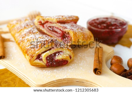 
Raspberry roll with jam on cutting board with autumn decoration on white background. Close up. Dessert concept