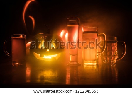 Glasses of cold light beer with pumpkin on a wooden table for Halloween. Glasses of fresh beer and pumpkin on a dark toned foggy background