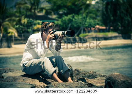 Man sitting on Lava rocks taking pictures in Hawaii