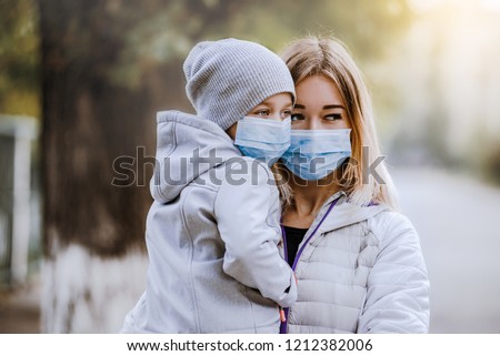 a girl with a child stands on the road in a protective medical mask. Dense smog on the streets. Epidemic of the flu Royalty-Free Stock Photo #1212382006