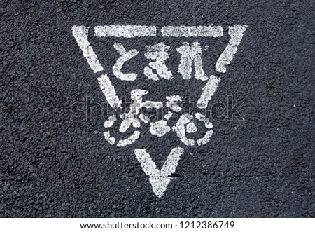 Japanese hirakana language word with bicycle sign on balck concrete street ground, mean as stop place to looking safty for who ride a bic.