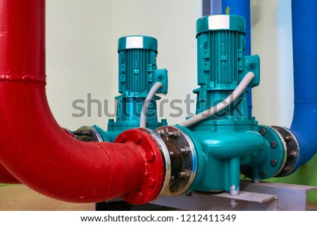 Two vertical engine painted blue with pumps connected to pipes painted red and blue.