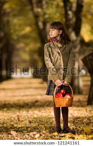 happy beautiful little girl stand on autumnal  leaf  with apple