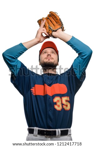 Player just caught a ball. Young bearded guy playing baseball as a pitcher, holding ball in hands over head. Winner concept.