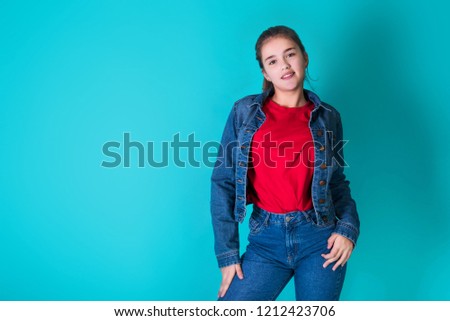 Beautiful cheerful teen girl over blue background. Cute emotions teenager. Wearing stylish casual clothes. Space for text. Cute teenage school girl